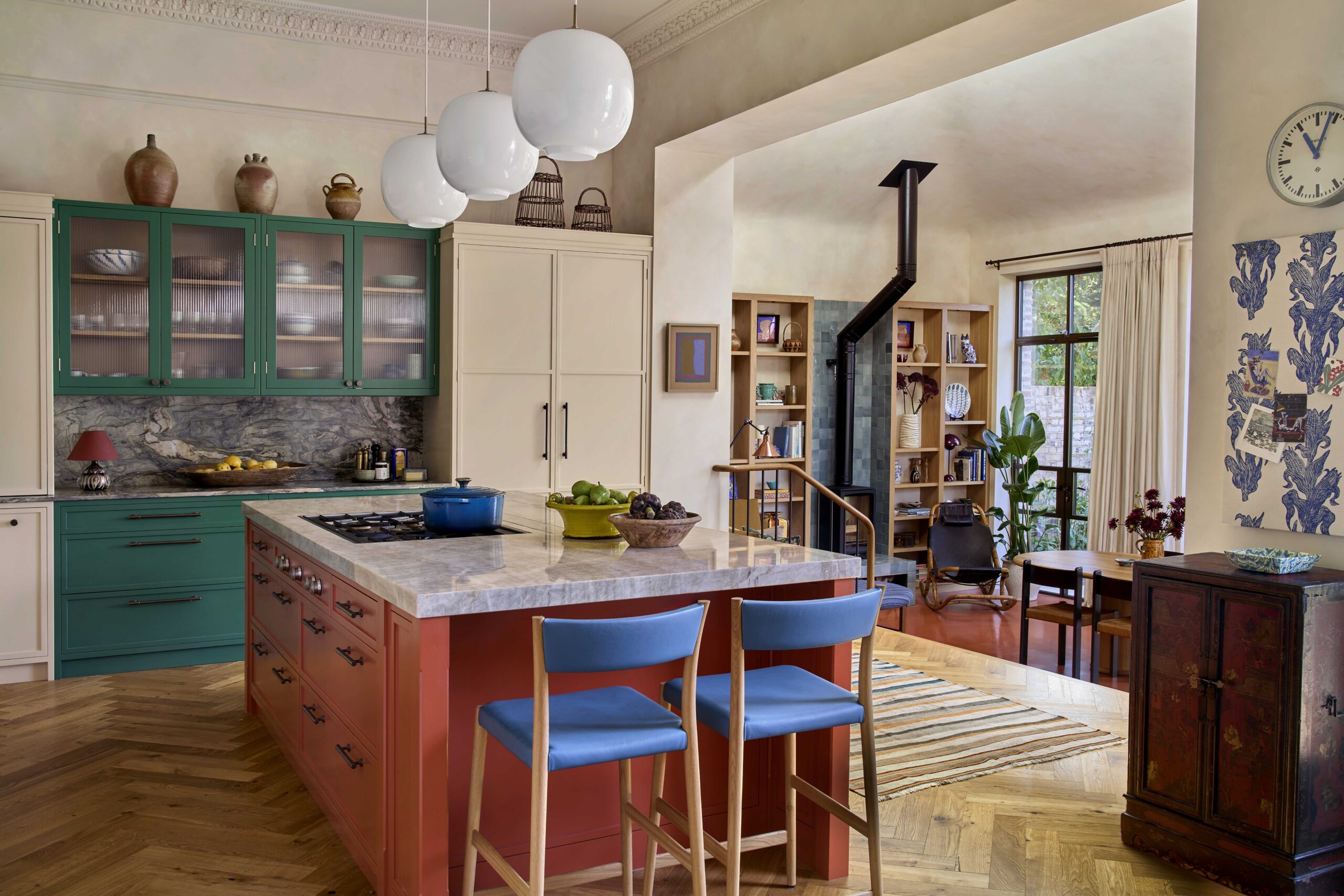 Bright kitchen featuring a coral island with blue stools and green wall cabinetry