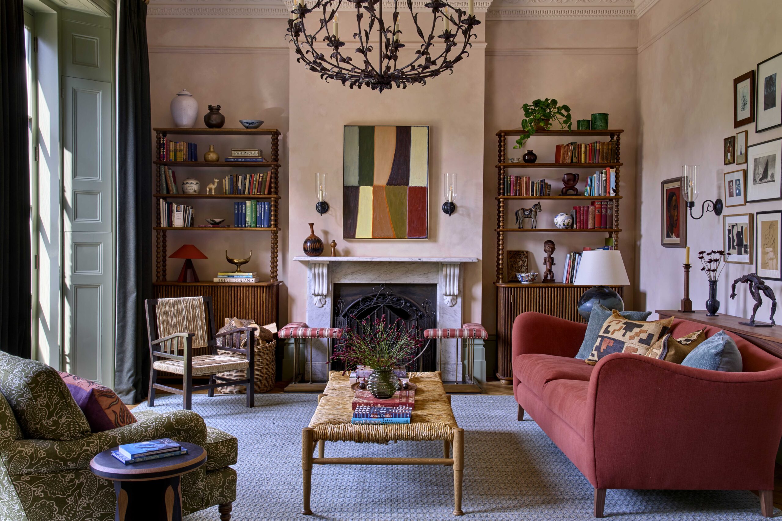 Living room with soft pink walls, a warm coral sofa, and a striking black chandelier