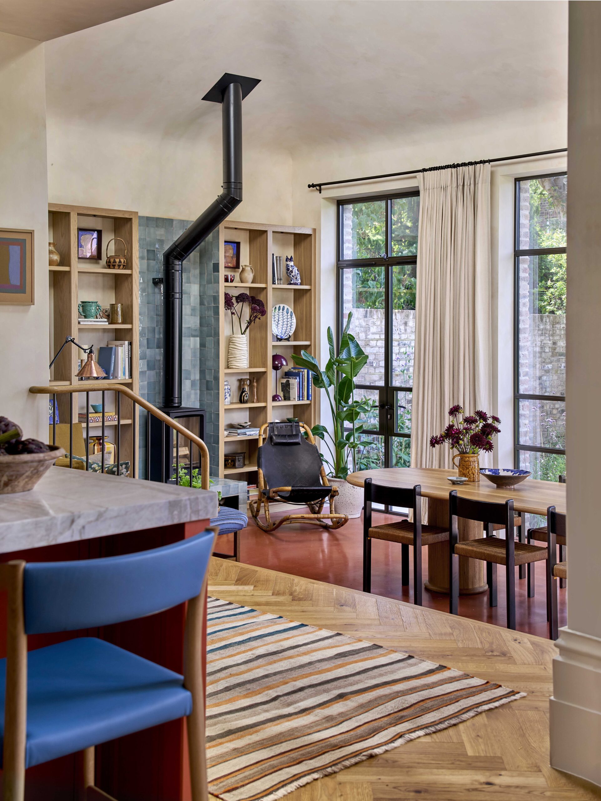 Dining area featuring built-in wooden shelves, a black stove, and large metal-framed windows